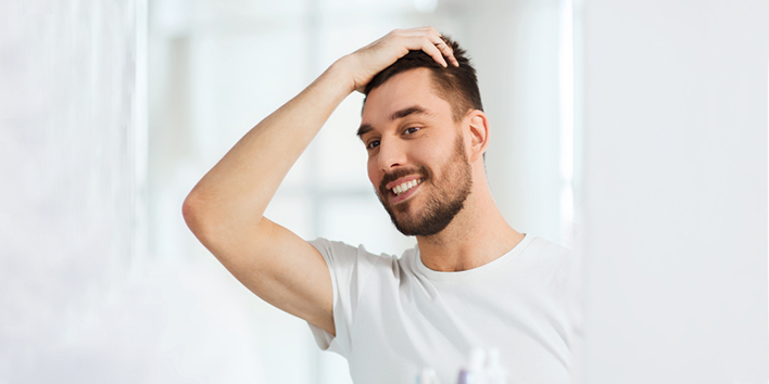 Man looking in mirror and touching hair